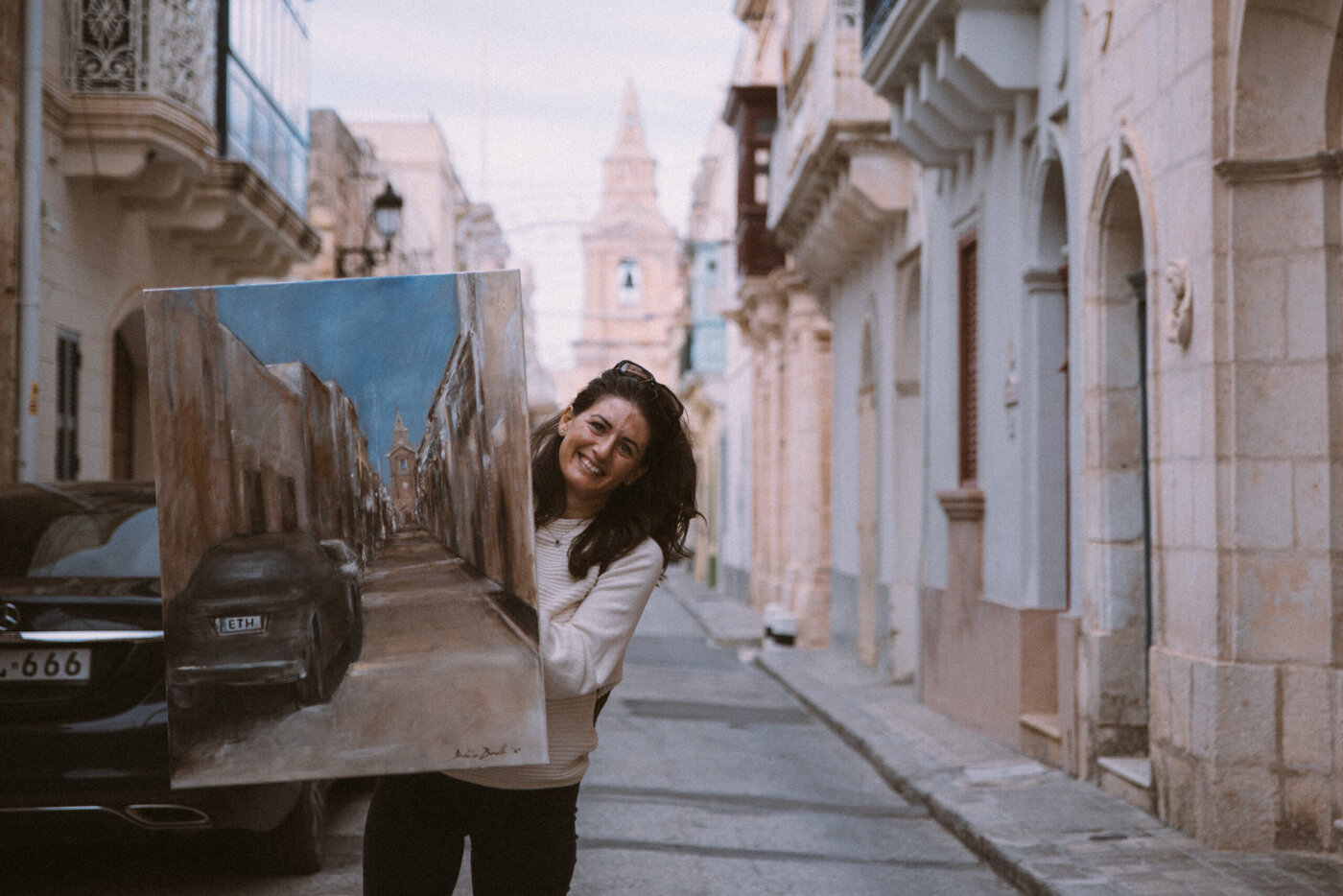 Woman holding painting of street scene