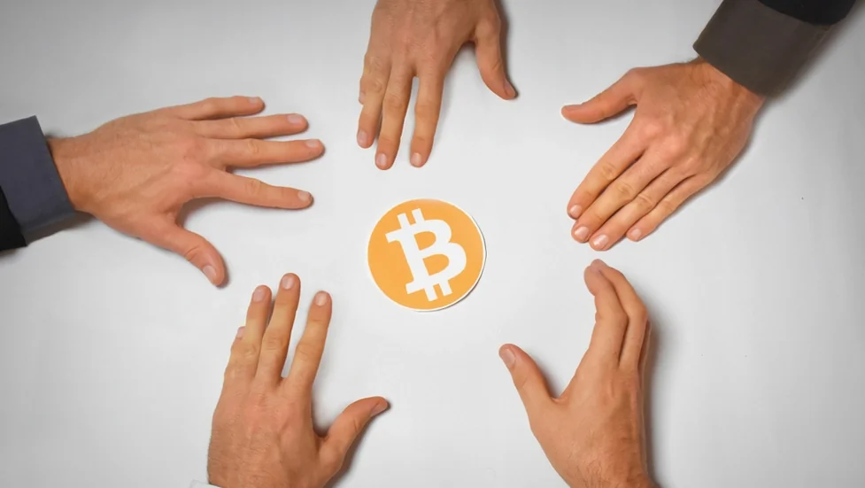 Hands reaching for Bitcoin