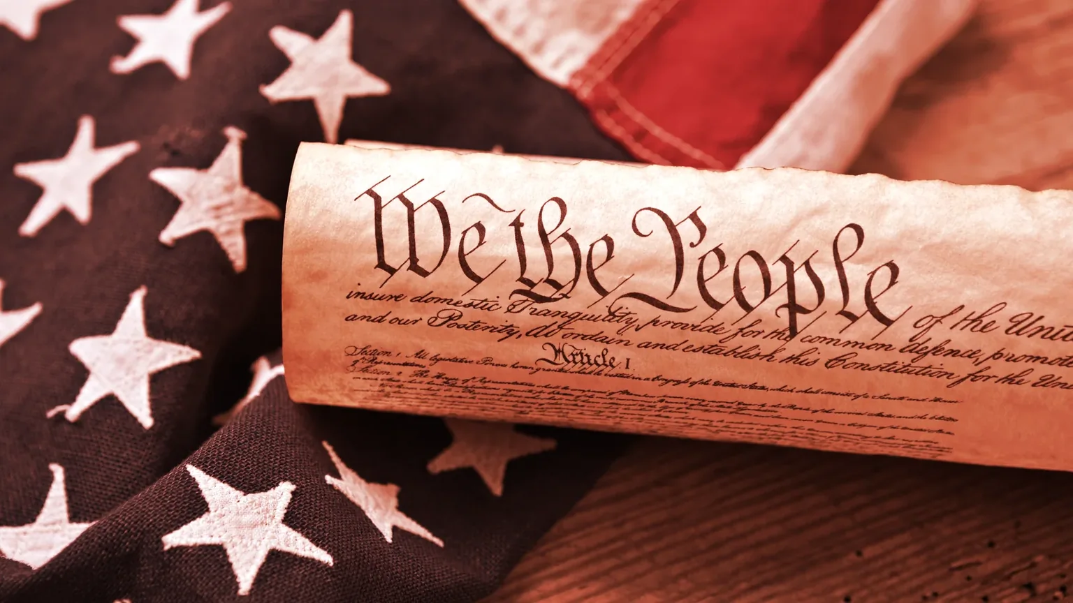 United States Constitution, rolled in a scroll on a vintage American flag and rustic wooden board. Image: Shutterstock