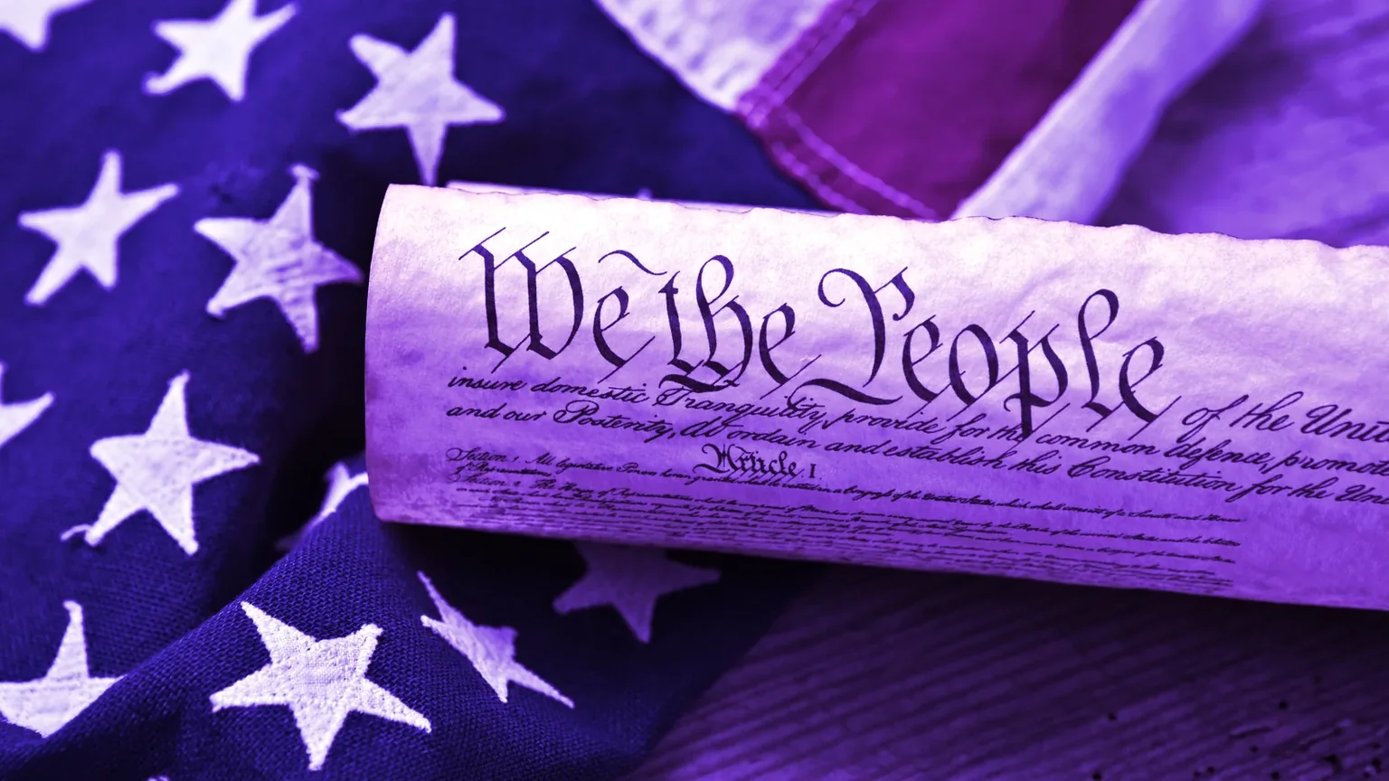 United States Constitution, rolled in a scroll on a vintage American flag and rustic wooden board. Image: Shutterstock