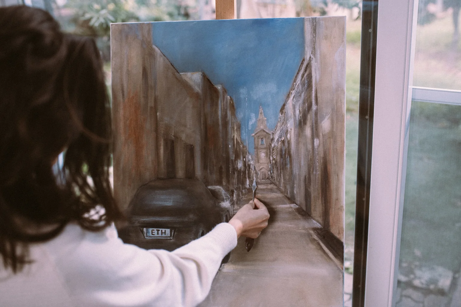 Woman painting street scene in artist's studio