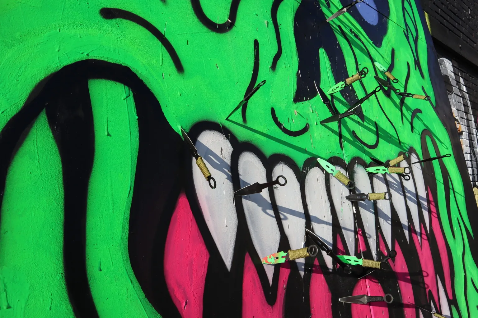 Closeup photo of Will Carsola's painting of the green demon's mouth with knives thrown at him.
