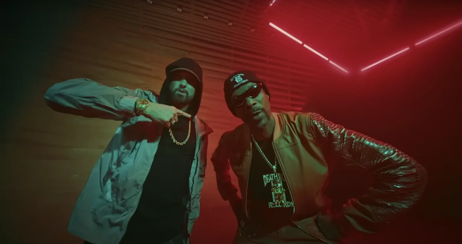 Snoop Dogg y Eminem rapeando con iluminación verde y roja de fondo.