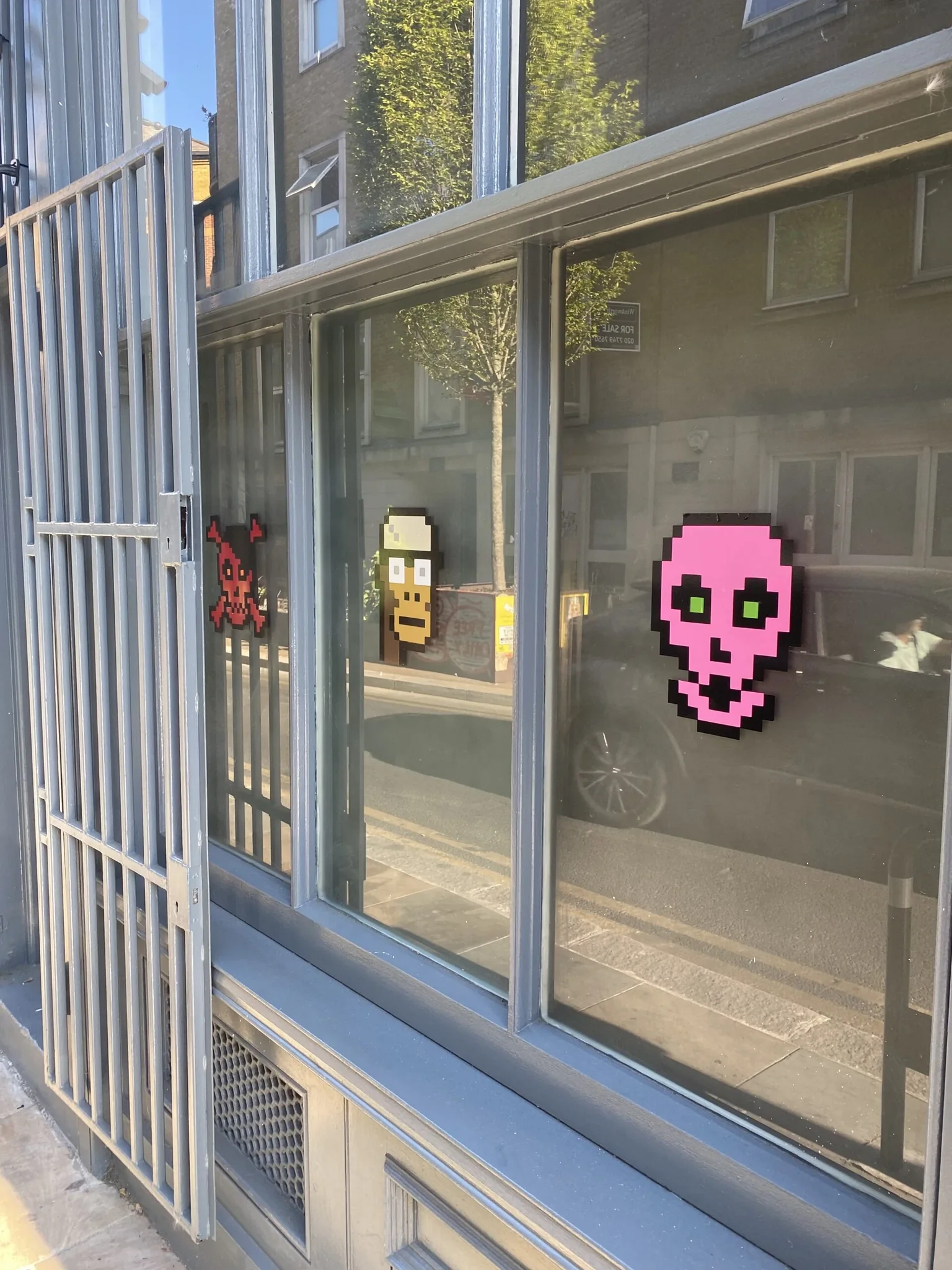 Outside of a shop with tinted windows and images of an Ape CryptoPunk NFT and a Cryptoskull NFT.